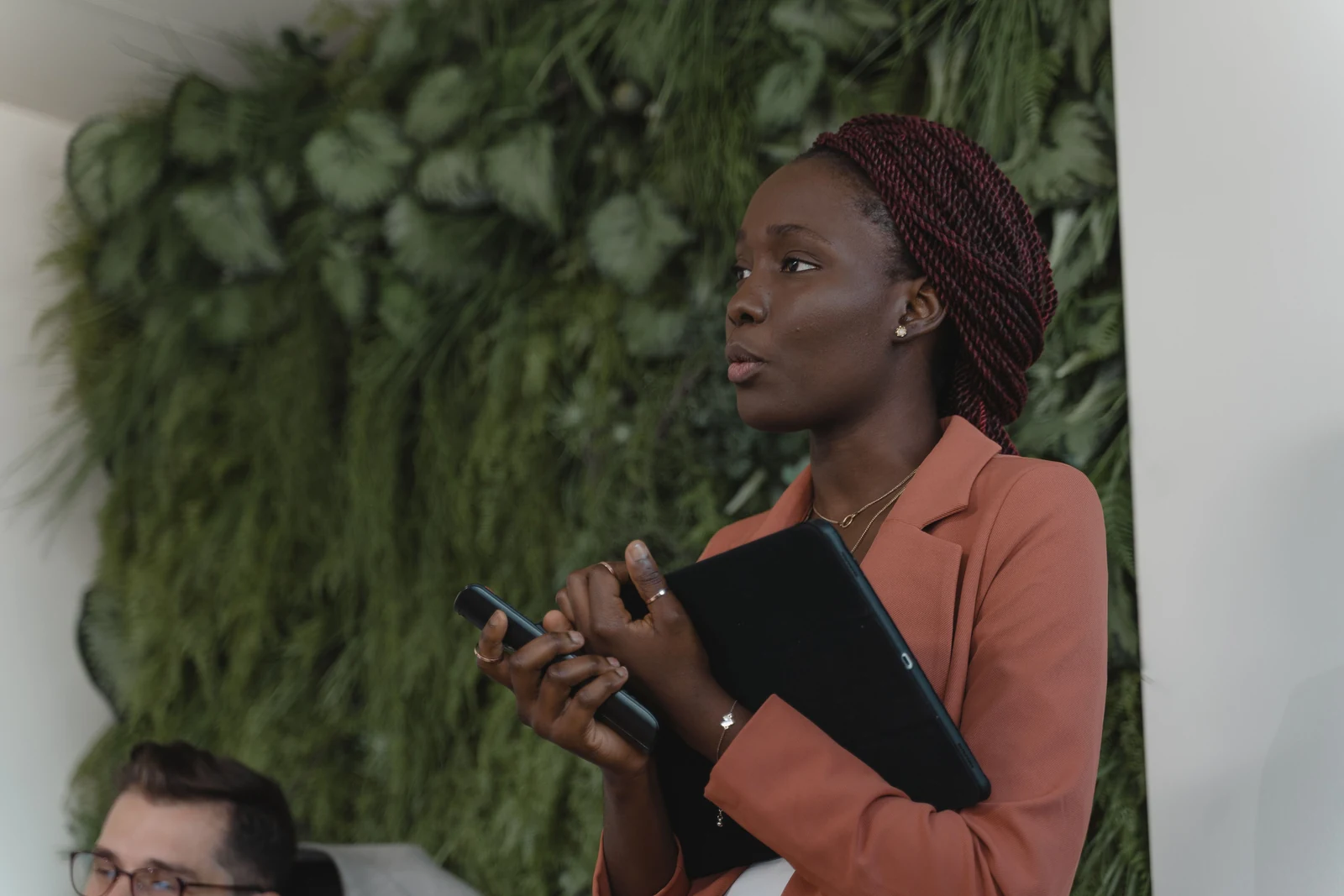Woman standing and speaking confidently in a work meeting, holding a tablet