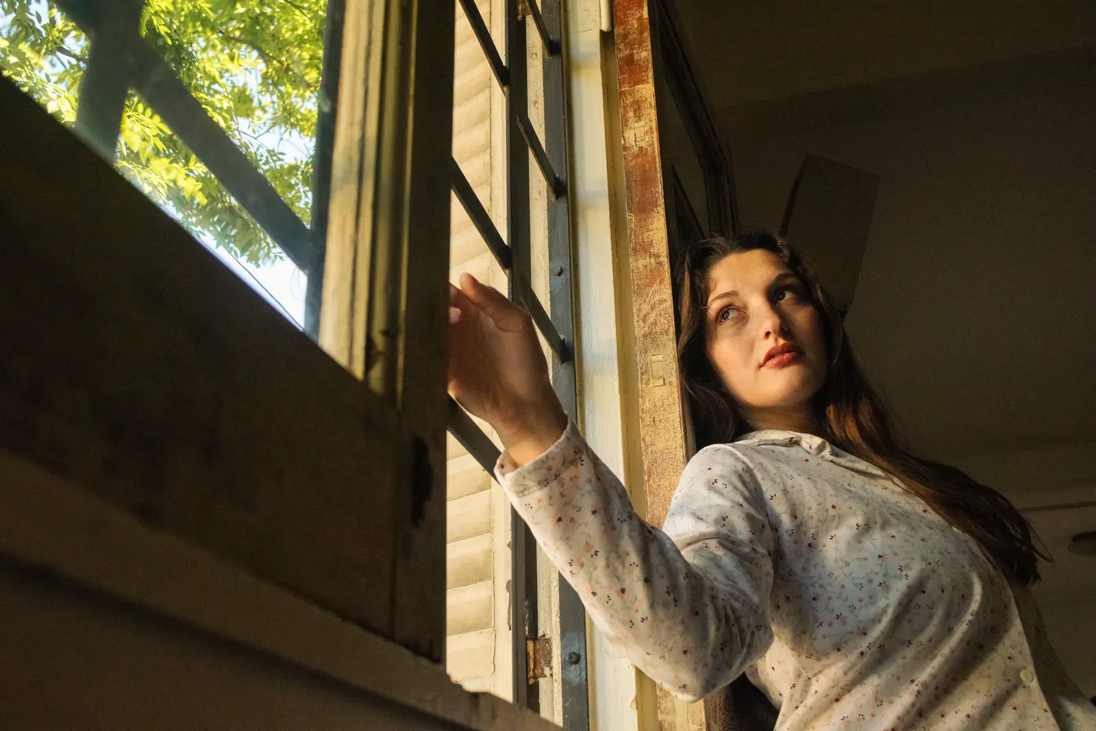 Woman opening a window and looking out into sunlight, a moment of clarity during perimenopause